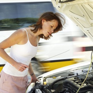 Young Woman Standing Over a Car Engine Bay Checking An Oil Dipstick